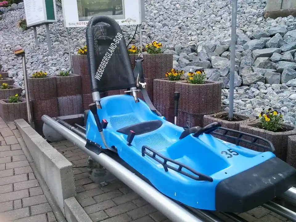 Blauer Schlitten eines Alpine Coasters mit zwei Bremshebeln, abgestellt auf der Schiene